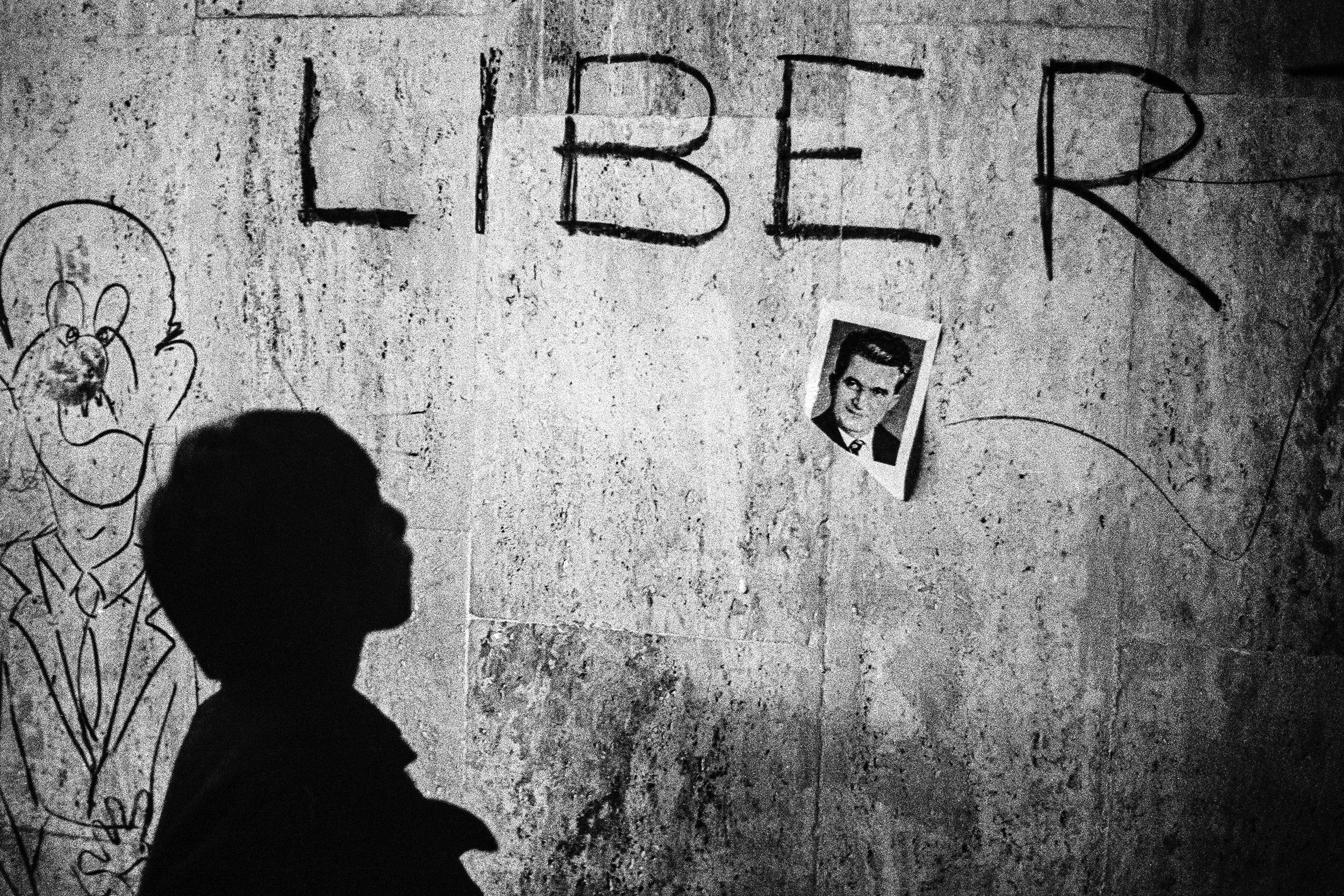 Na fotografii přilepené na zdi je Nicolae Ceaușescu. Jen o několik dní později bude diktátor po krátkém procesu zastřelen.